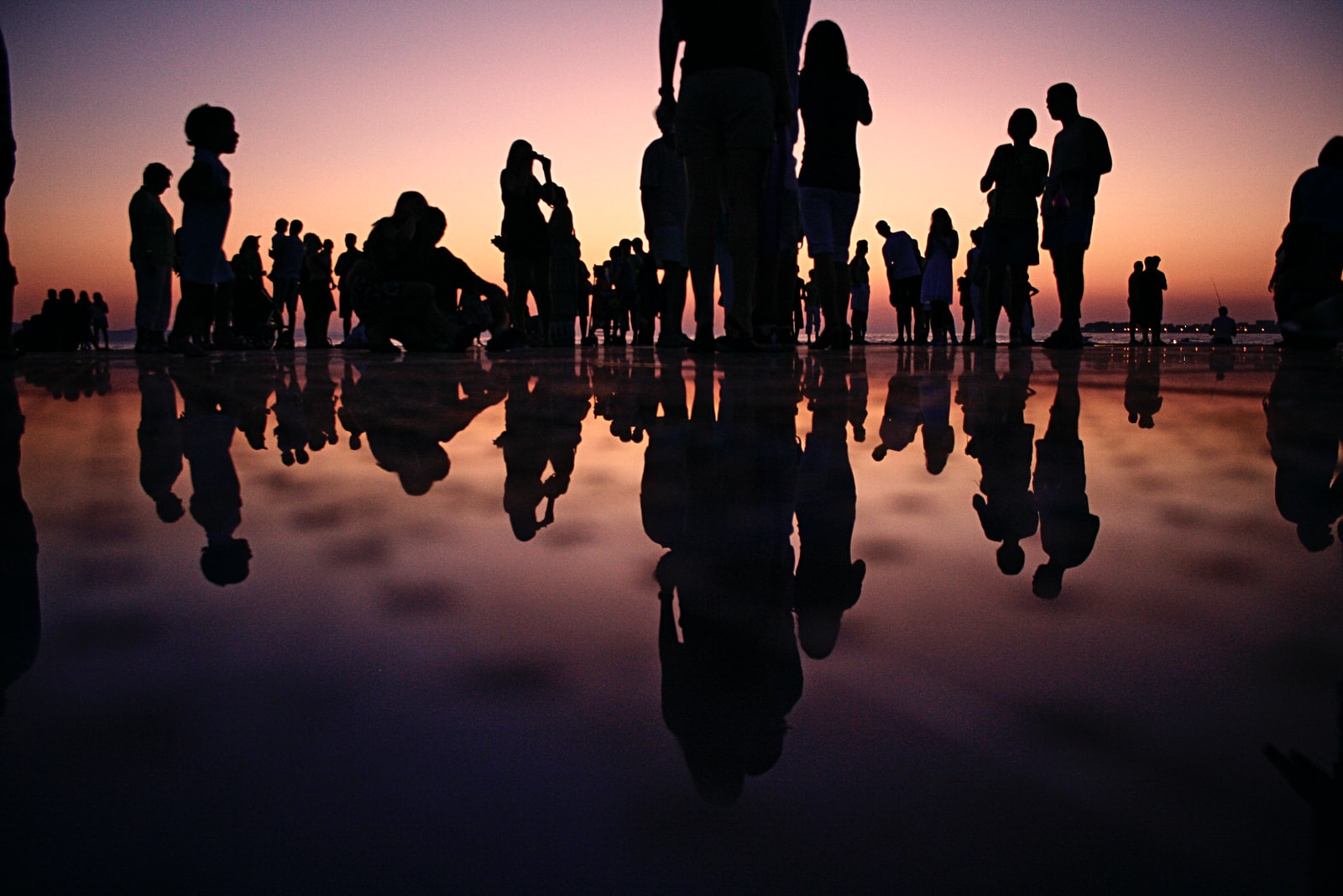 Many people, silhouetted against sunset